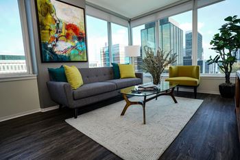 A living room with a grey couch and yellow pillows.